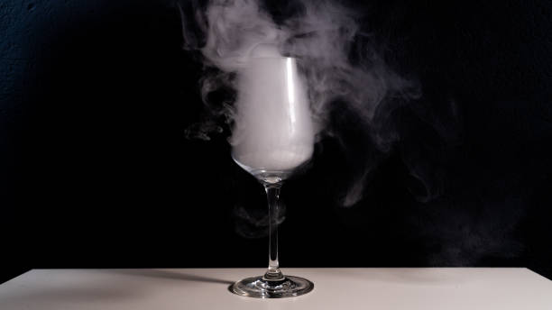 istock wine glas filled with smoke on a white table with a black background, smoke in glas, 1067896452