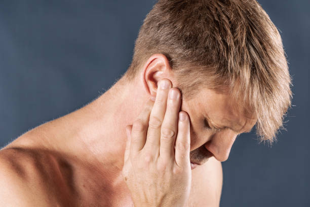 istock Man has a sore ear. Man suffering from headache on blue background 1067899910