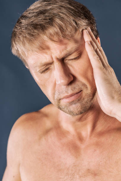 istock A man holds his hands on his head on blue background. Headache or migraine. 1067899918