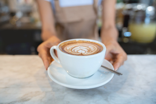 Close-up on a waitress serving a cup of coffee at a cafe - small business concepts