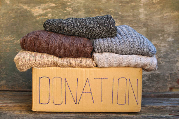 istock Donation box with warm things on old wooden background. 1067918182