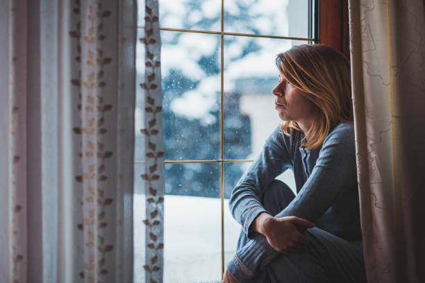istock Sad woman sitting by the window looking outside 1067934096