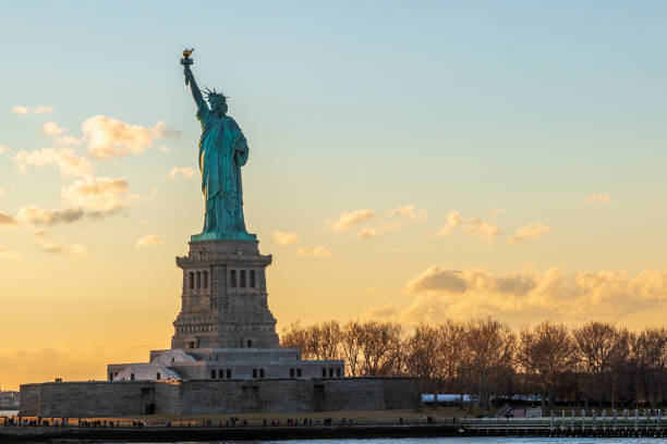 statue de la liberté horizontale pendant le coucher du soleil dans la ville de new york, ny, é.-u. - dusk people manhattan new york city photos et images de collection