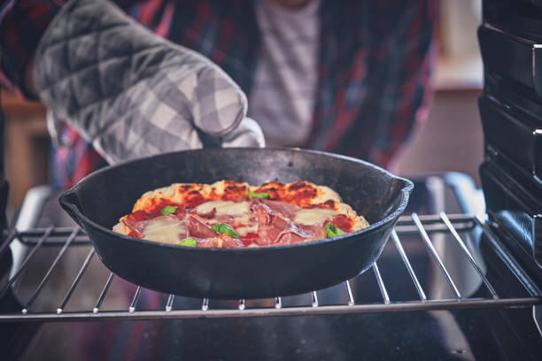 istock Preparing Pizza with Mozzarella and Ham in a Pan 1067939236
