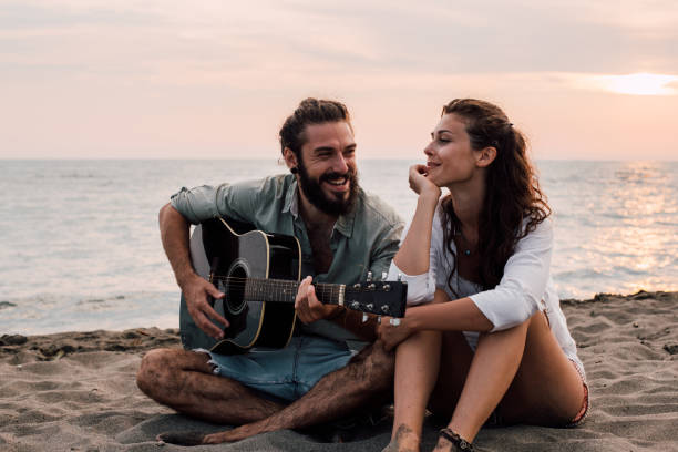 istock Smiling couple with guitar at the beach 1067941358