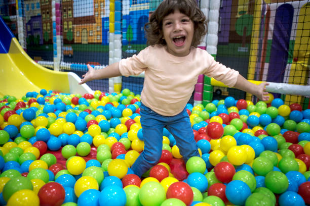 istock Little Boy sitting and playing with multicolored plastic balls 1067941886