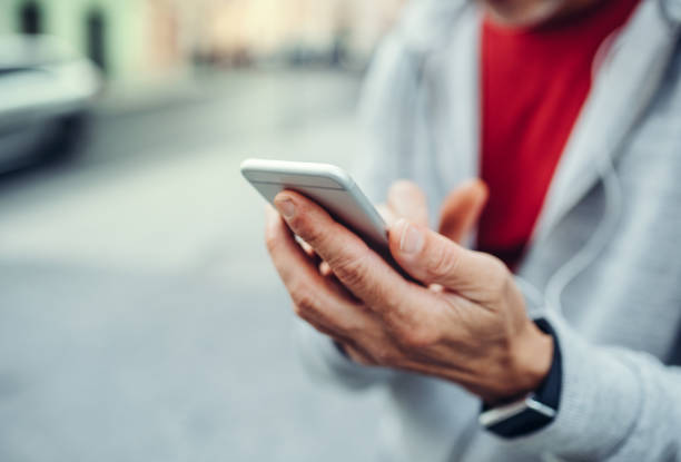 un primer plano de hombre irreconocible permanente al aire libre en la ciudad, con smartphone. - one mature man only fotografías e imágenes de stock