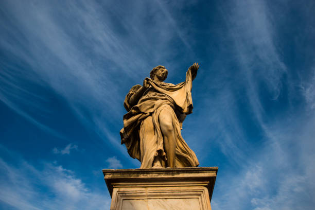 A statue of a man stands in front of a blue sky