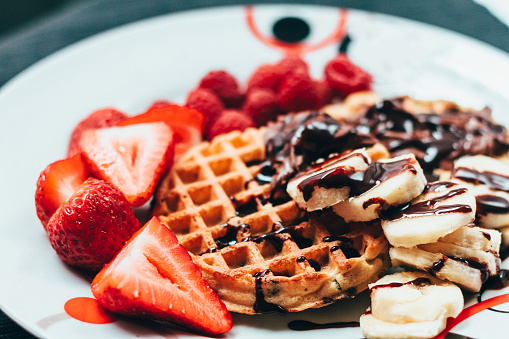 Traditional waffles and strawberries, with bananas and chocolate