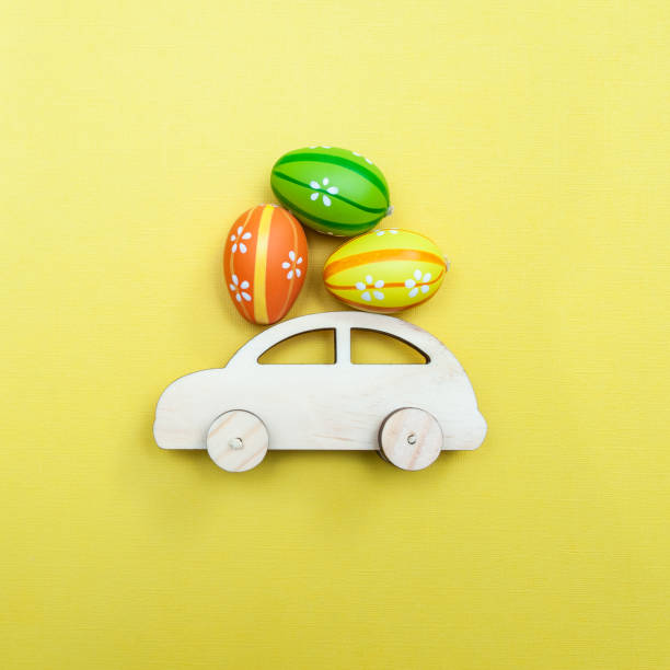 istock Easter theme. Car with Easter eggs on a yellow monophonic background. Minimalism, top view, flat. 1067946796