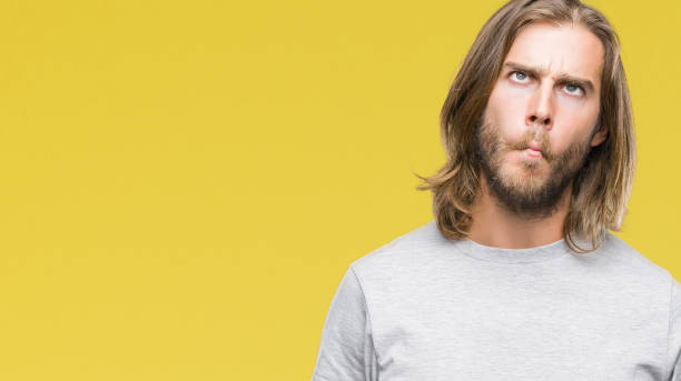 istock Young handsome man with long hair over isolated background making fish face with lips, crazy and comical gesture. Funny expression. 1067947092