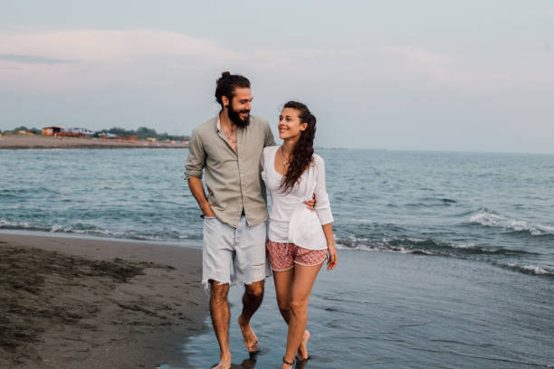 istock Couple hugging and walking down the beach 1067950750
