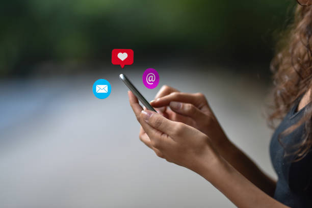 istock Young woman using smart phone with social media symbols 1067962728
