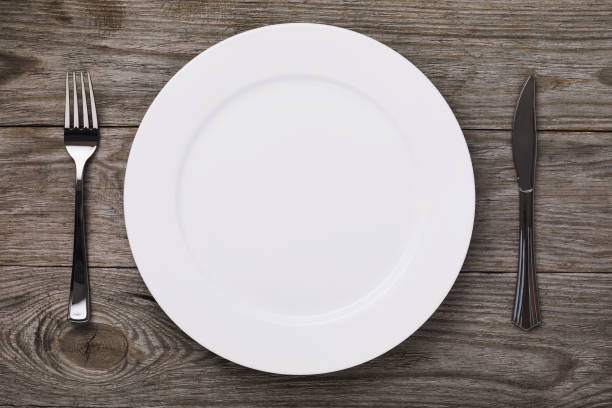 istock Empty white ceramic plate and cutlery on a village table, top view 1067968962