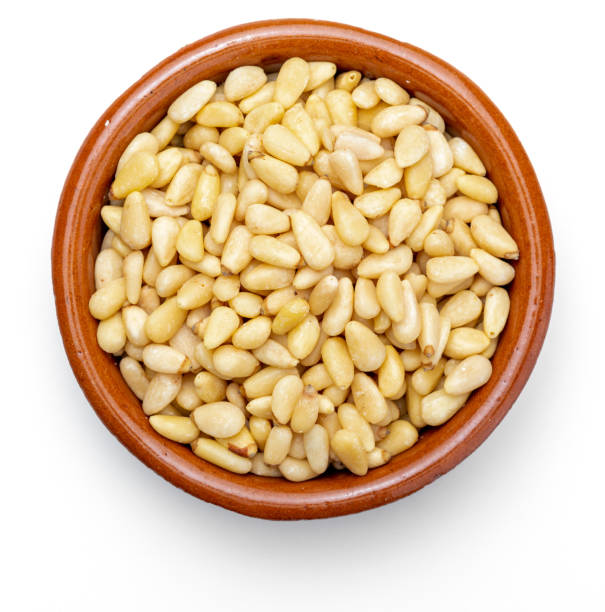 istock Peeled pine nuts. In clay container. Aerial view (from above, top view). Foreground (Close-up). Isolated on white background. 1067974122
