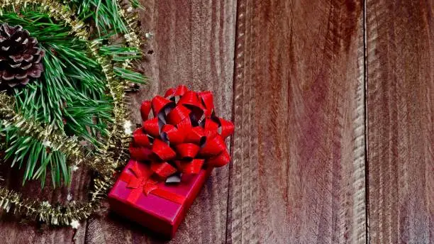 Christmas box with pine branches, ribbon and wooden background.