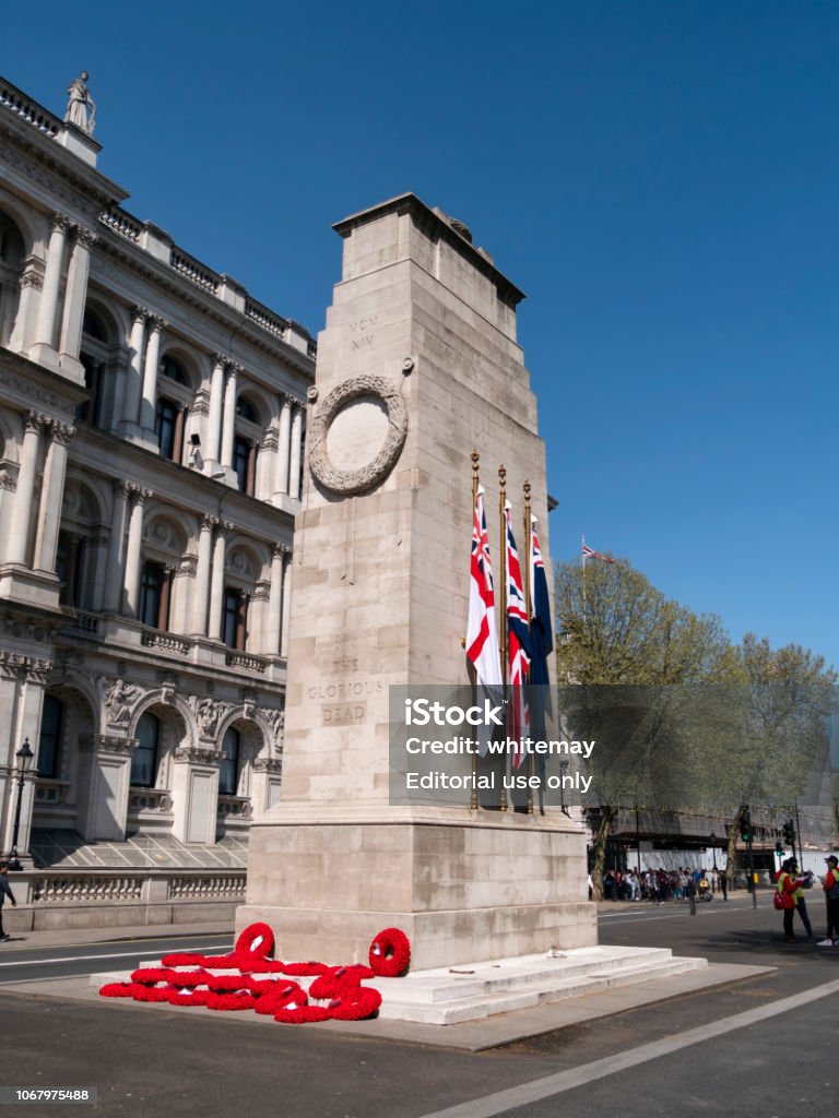 Wreaths and flags on The Cenotaph in Whitehall, London A collection of red poppy wreaths at the foot of The Cenotaph in Whitehall, London, on a sunny day in springtime. The Cenotaph is a war memorial designed by Edwin Lutyens where the national remembrance service has taken place since its construction in 1920 following World War One. The standards of the three services in the British armed forces are on display - navy, army and air force. (Incidental people.) The Cenotaph Stock Photo