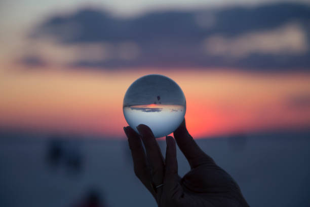 istock woman's hand with crystal ball Sunset 1067979998