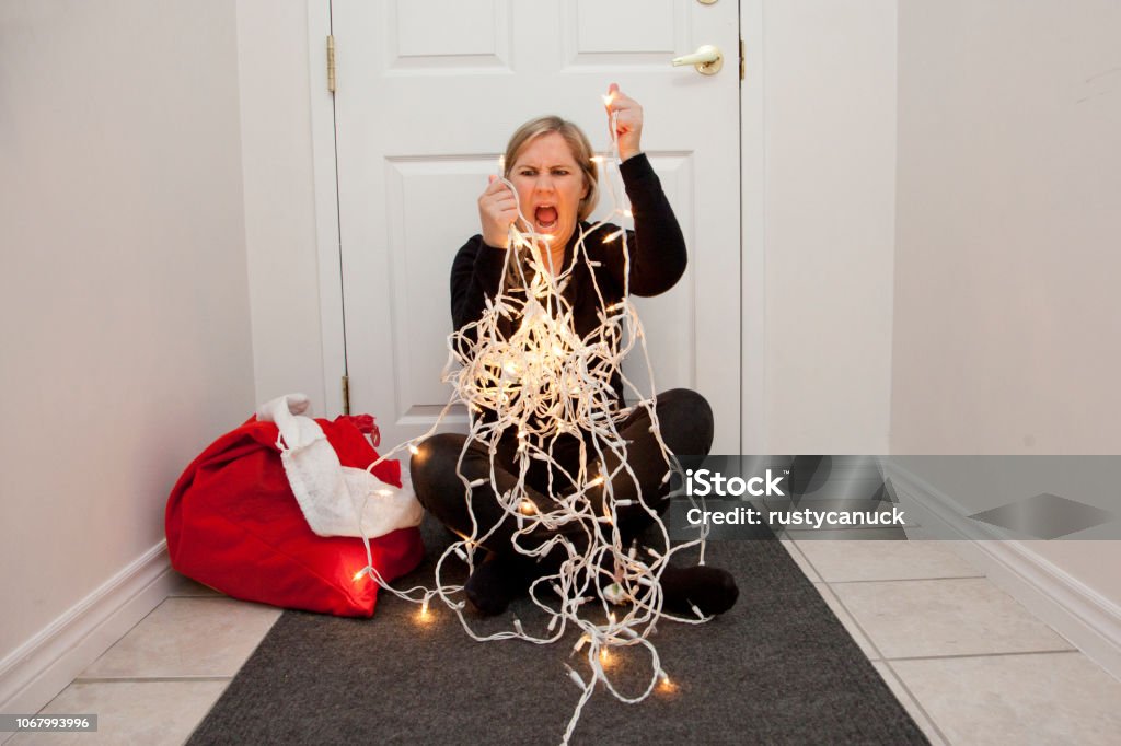 Screaming at the Christmas lights A frustrated woman can't get the christmas lights to untangle so she screams in anger Christmas Stock Photo