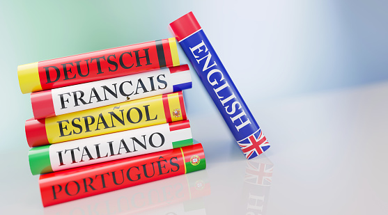 Stack of colorful dictionaries in front of defocused background. English, German, Portuguese, Spanish, French and Italian dictionaries are sitting on top of each other. Horizontal composition with copy space.