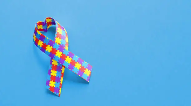 Heart shaped autism awareness ribbon on blue background. World autism awareness day concept. Horizontal composition with copy space.