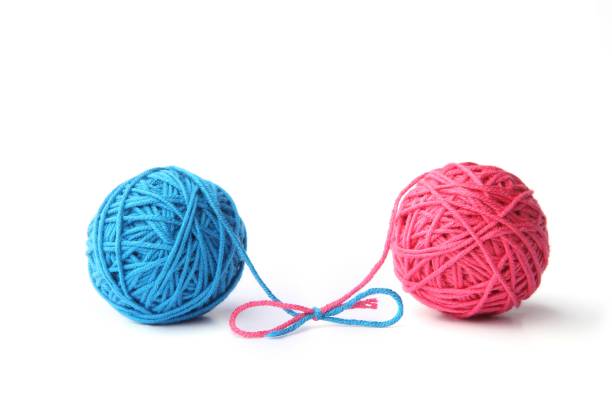 istock Two pink and blue cotton thread balls tied in bow isolated on white background. 1068031174