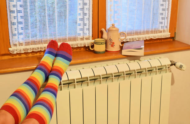 istock Central heating radiator and woman in striped socks 1068036004