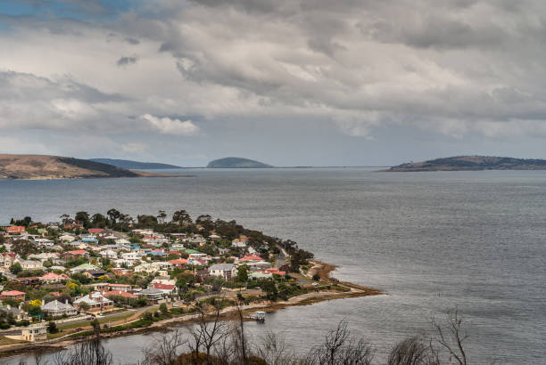 Hobart, Tasmania, Australia - December 13. 2009: Posh Bellerive neighborhood and peninsula across Derwent River from dowtown Hobart under cloudy gray sky. Looking towards the sea over gray water.