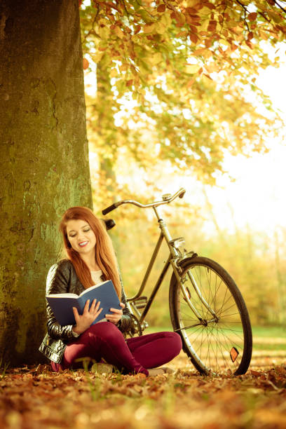 istock Pretty girl is reading, sitting uder the tree. 1068043552