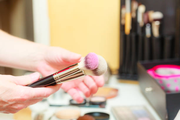 istock Person holding makeup brushes for blush and powder 1068045224