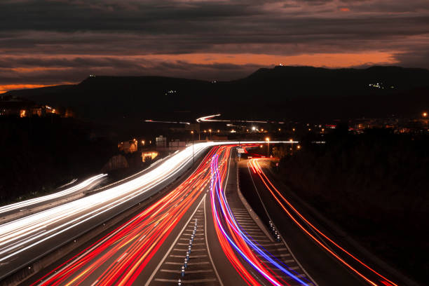 istock Urban Highway Light Trails and Colorful Sunset Dark Scene 1068047200