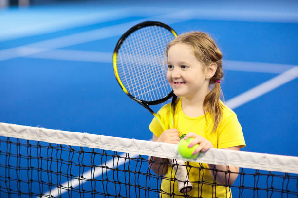 ребенок играет в теннис на крытом корте - tennis court indoors net стоковые фото и изображения