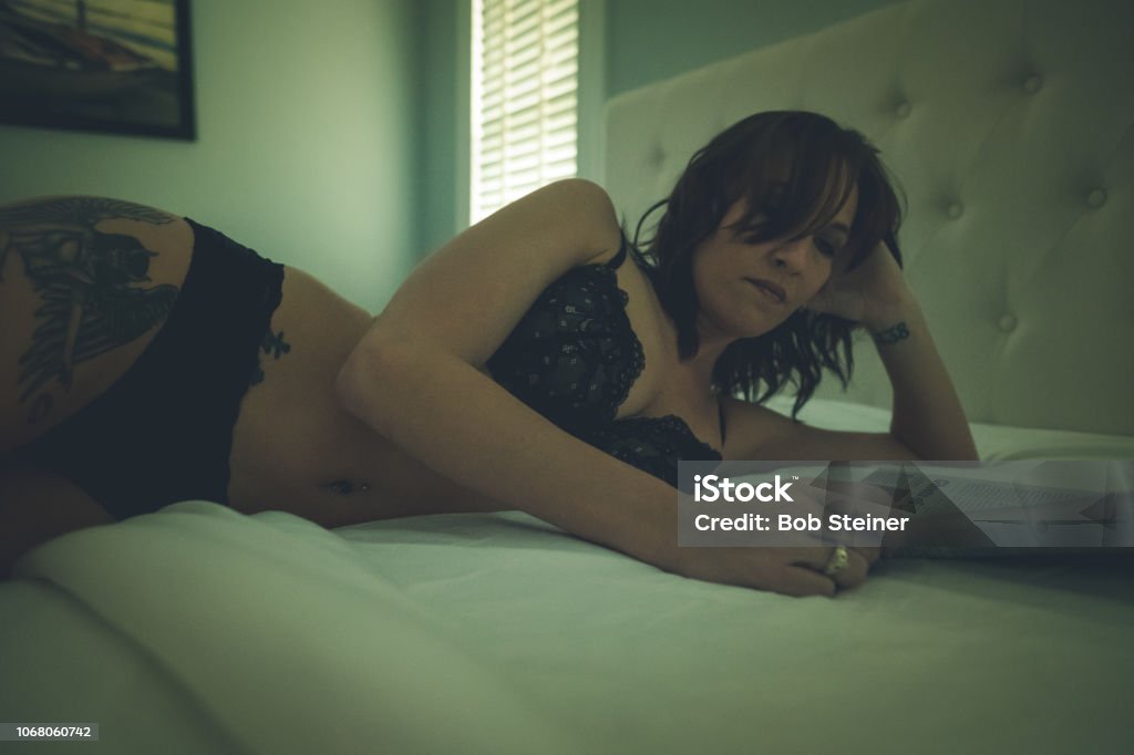 Sunday Morning A young woman lies in bed wearing black lingerie while reading during the early morning hours. Seductive Women Stock Photo