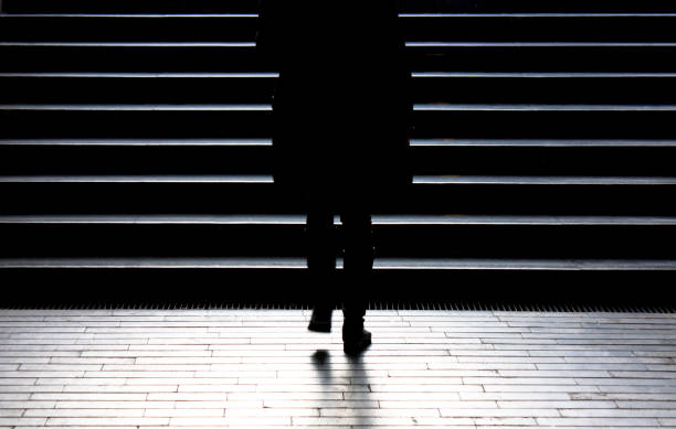 Blurry silhouette of young woman climbing up the city street stairs in winter moonlight stock photo