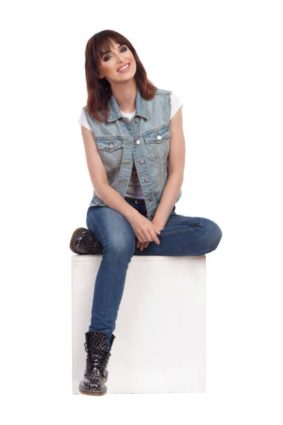 istock Beautiful Woman Is Sitting On A White Box, Looking At Camera And Smiling 1068073988