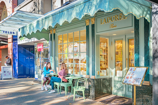 People relax at a luxury patisserie on Robson Street, a shopping street in downtown Vancouver, British Columbia Canada, on a sunny day.