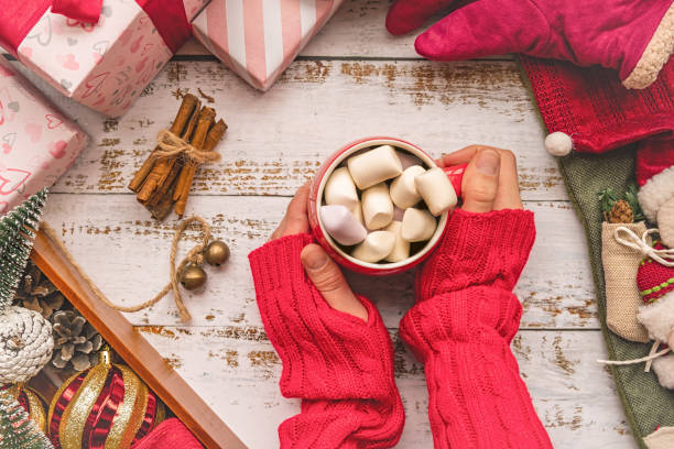 istock woman hands holding a Christmas mug with marshmallows on white rustic background surrounded with decorations 1068094828