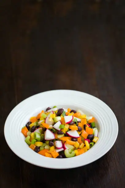 Vegan and vegetarian bean salad with black beans, orange and yellow bell peppers, radish, celery and scallions.