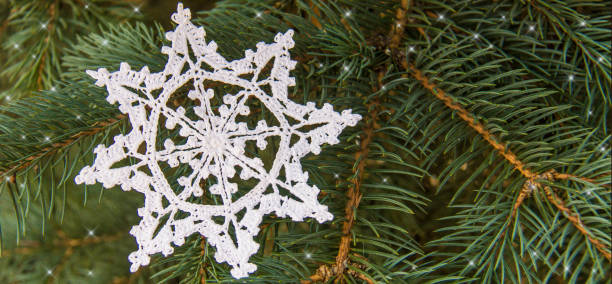 istock White cotton crocheted snowflake on green christmas fur tree 1068108600