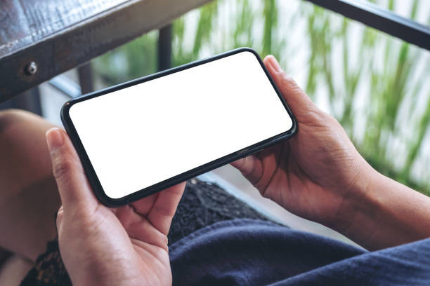 istock Mockup image of a woman holding black mobile phone with blank desktop screen while sitting in cafe 1068143360