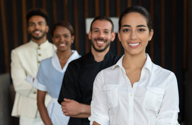 Beautiful female manager and her team standing behind all looking at camera smiling Beautiful female manager and her team standing behind all looking at camera smiling - Focus on foreground concierge service stock pictures, royalty-free photos & images