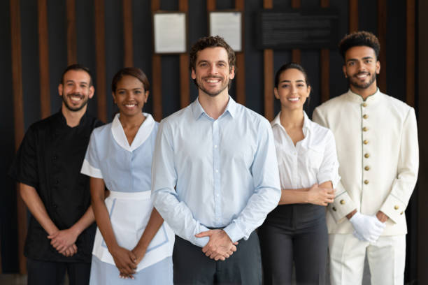 Multi ethnic group of workers at a luxury hotel all looking at camera smiling Multi ethnic group of workers at a luxury hotel all looking at camera smiling  very happy bellhop stock pictures, royalty-free photos & images