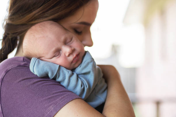istock Newborn baby sleeping on mother's shoulder 1068180364