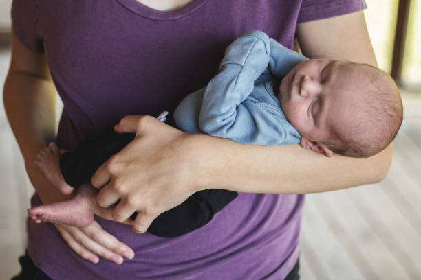 istock Sleeping newborn being held in mother's arms 1068180368