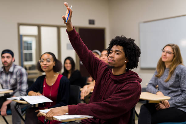 istock Black male college student raising his hand to answer a question during class 1068204456