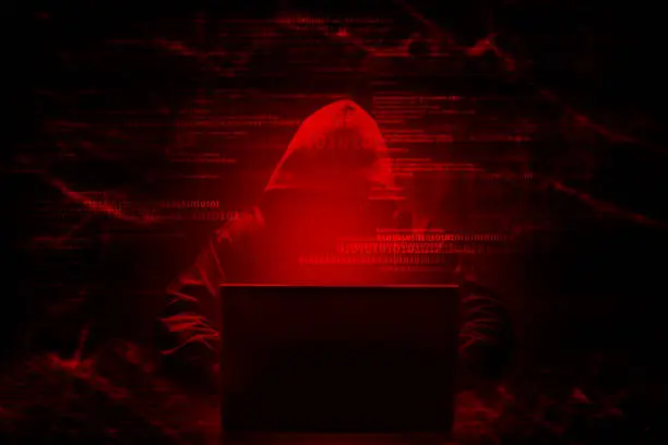 Photo of Internet crime concept. Hacker working on a code on dark digital background with digital interface around.