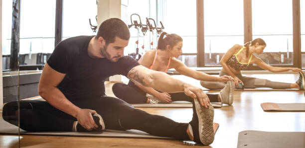 Together we can achieve our fitness goals. Small group of people stretching at the gym. Close up.