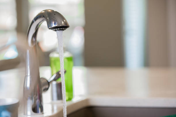 istock Faucet in modern kitchen running water into sink 1068248470