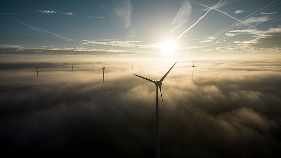Wind turbines in the morning fog shortly after sunrise