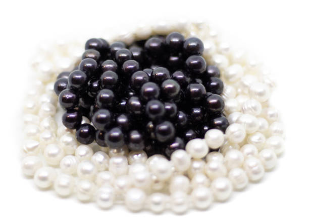 istock Two strands of white and black pearls on white background isolated 1068256420